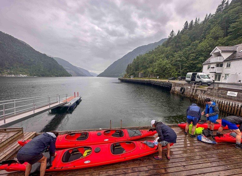 A lake with a dock, kayaks, and a building on the shore. 5