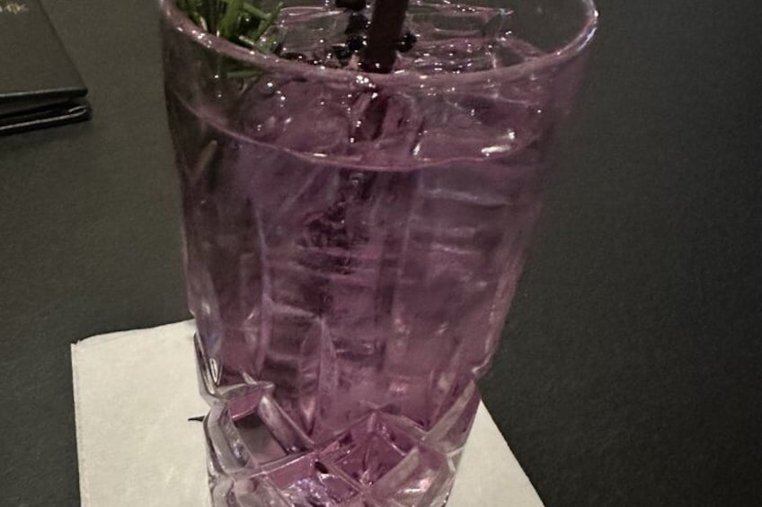 A purple glass with a straw and a napkin on a dark surface. 5