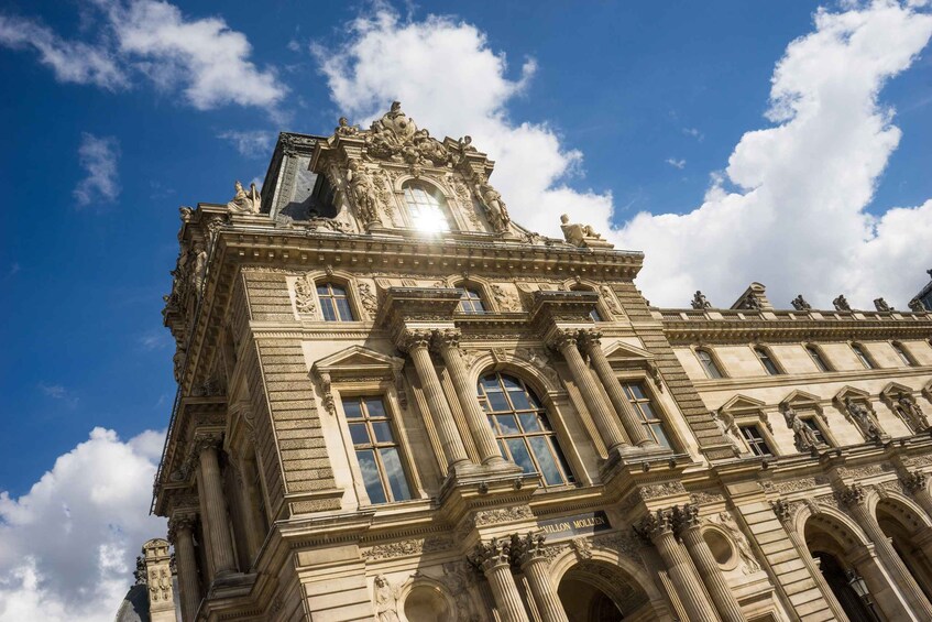 A historic building with ornate architecture, including columns and statues, under a clear blue sky. 2