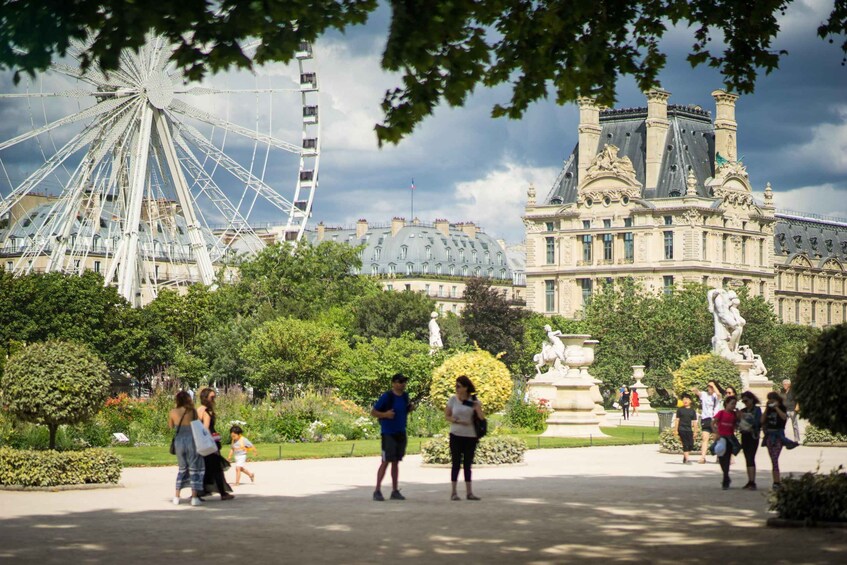 A park with a Ferris wheel, a large building with statues, and people walking. 4