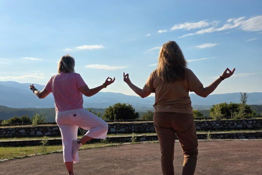 Two people practicing yoga outdoors with a mountainous landscape in the background. 4