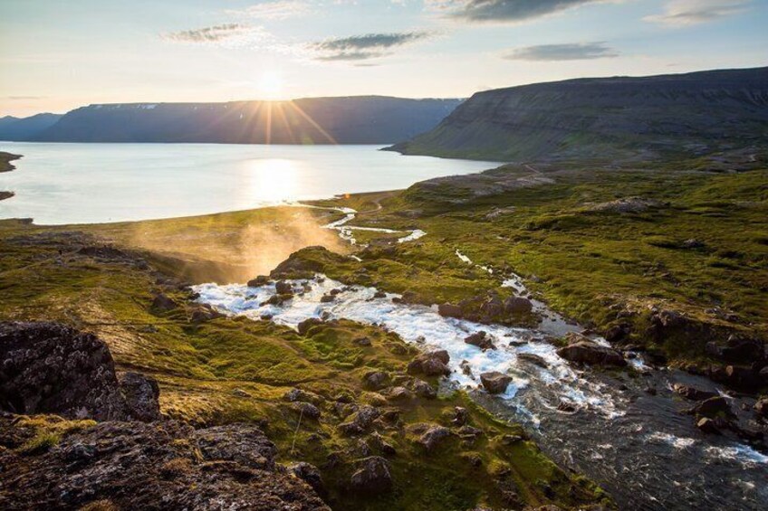 A coastal landscape with a body of water, grassy terrain, and rocky outcrops. 3