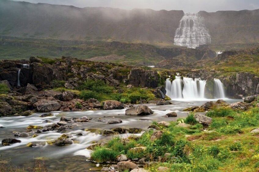A river with multiple waterfalls, surrounded by rocky terrain and greenery. 2