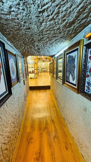 Taidegalleria, jossa on puulattia ja seinillä on kehystettyjä taideteoksia. 2