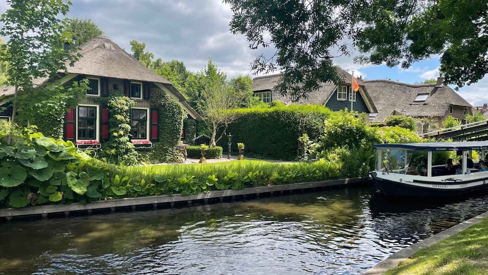 A canal with a boat, houses with thatched roofs, and lush greenery. 3