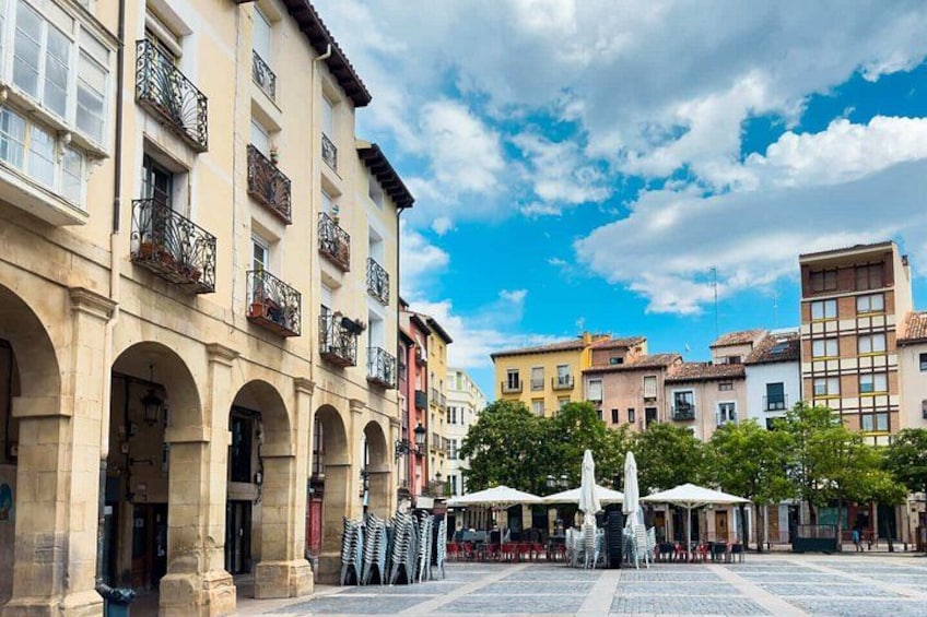 A historic square with buildings, a fountain, and outdoor seating. 5