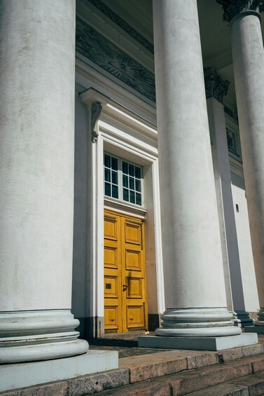 A building entrance with white columns and a yellow door. 4