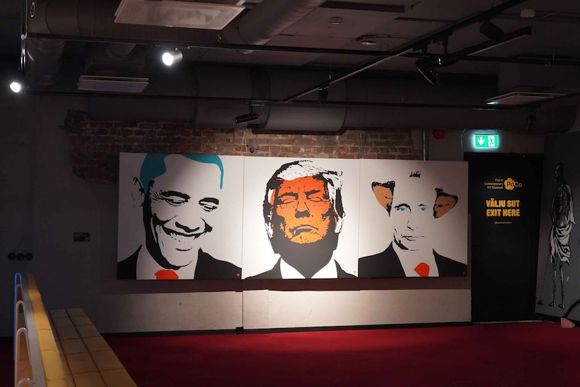 A wall with three large portraits, a red carpet, and an exit sign. 5