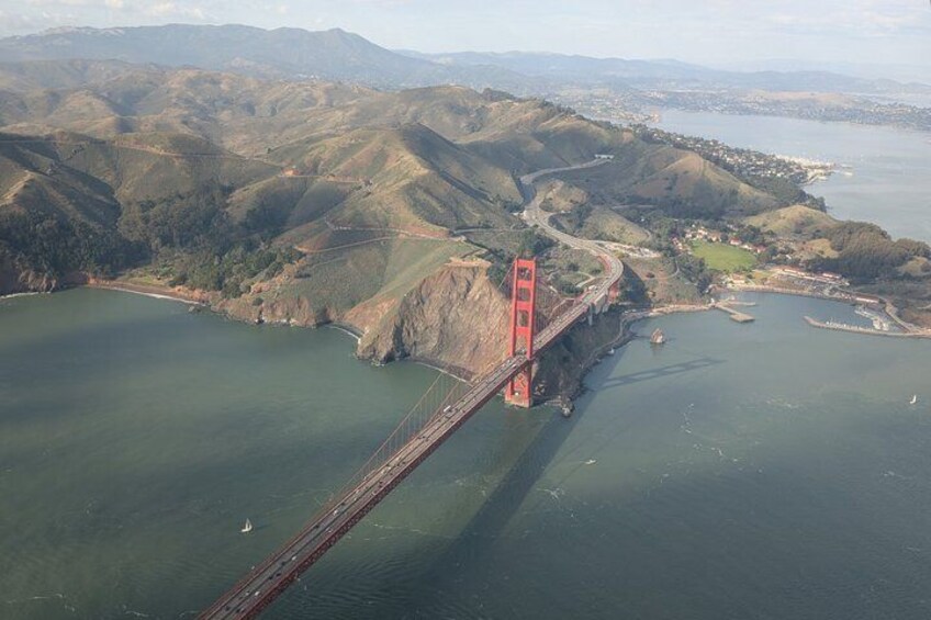A red bridge spanning a river with hills in the background. 1