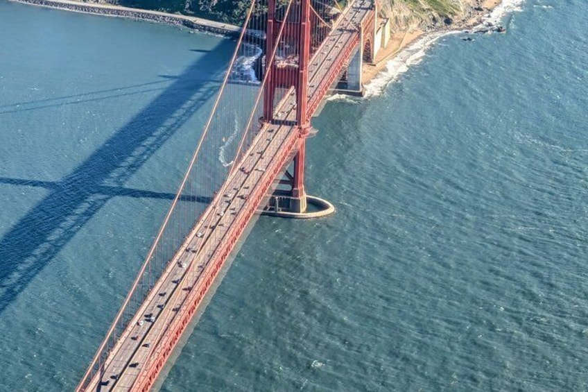 A red suspension bridge over a body of water with a clear sky. 5