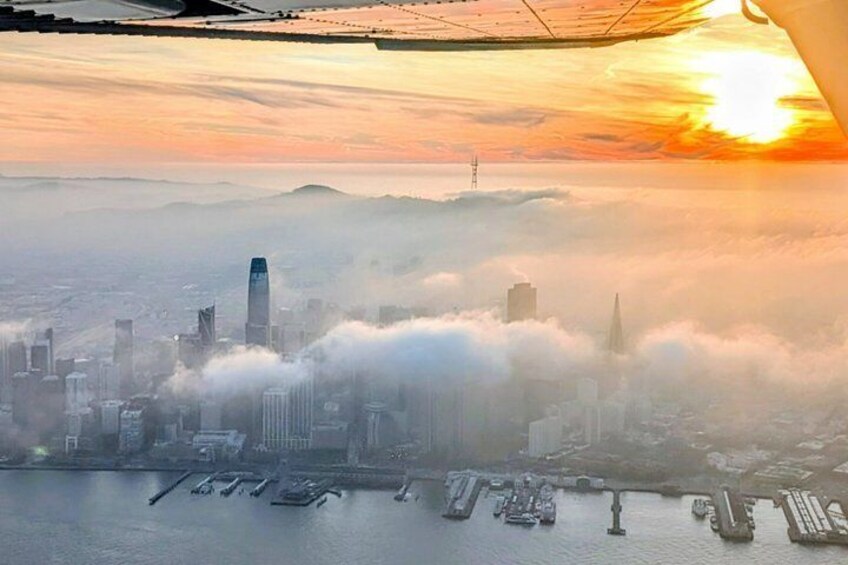 A cityscape with a prominent skyscraper, a body of water with boats, and a sunset. 4