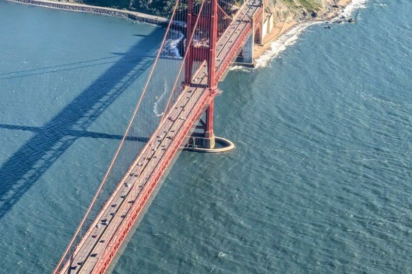 A red suspension bridge over a body of water with a clear sky. 4