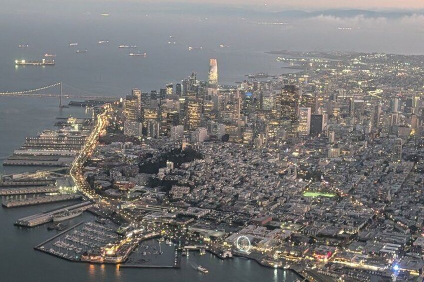 A coastal cityscape with a prominent bridge, dense urban buildings, and a marina. 3