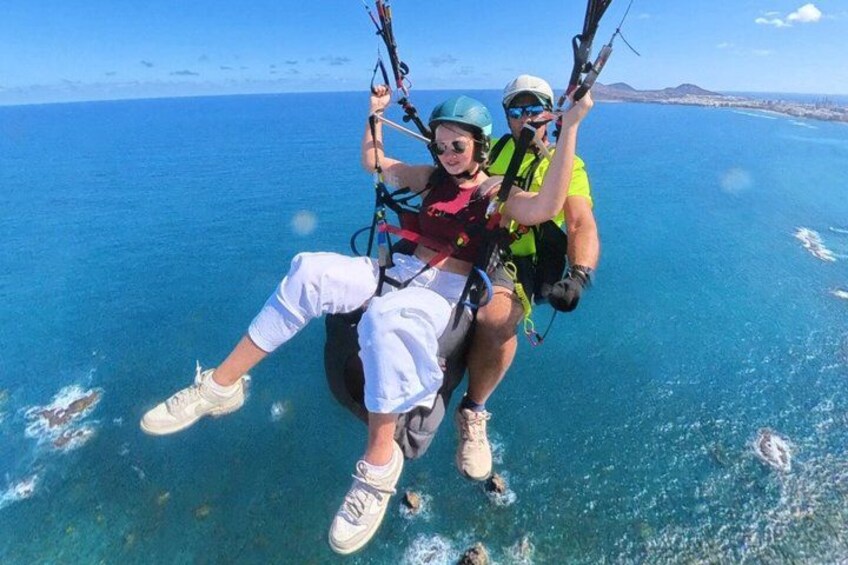 Two people paragliding over a body of water with a clear sky. 4