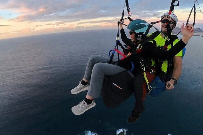 Two people paragliding over a body of water with a sunset in the background. 3