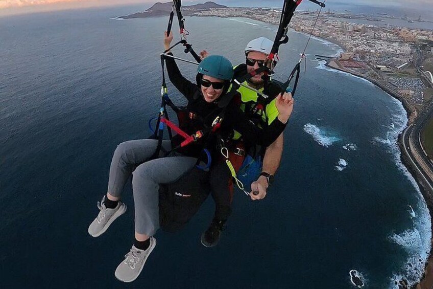 Two people skydiving over a coastal area with a view of the ocean and a distant cityscape. 5