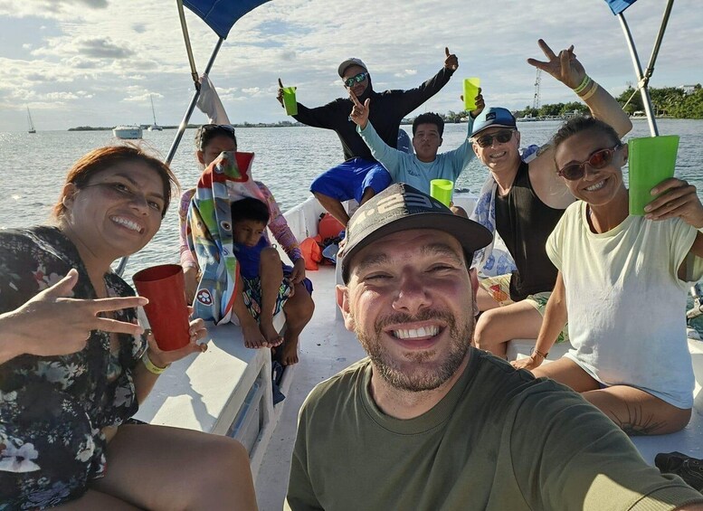 A group of people on a boat with a body of water and distant land in the background. 1