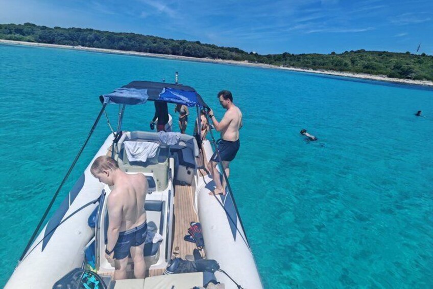 A boat on turquoise water with people on board and swimmers in the distance. 2