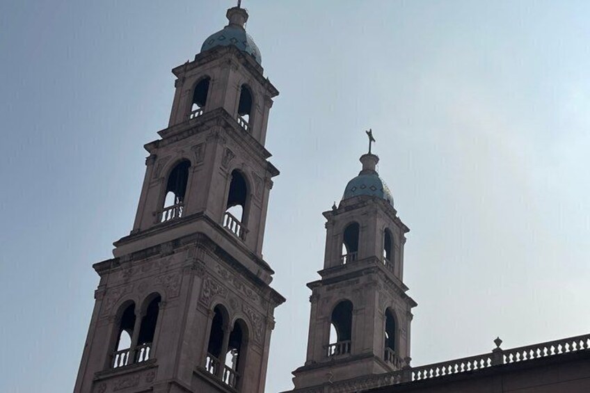 Two bell towers with arched windows and a dome. 5