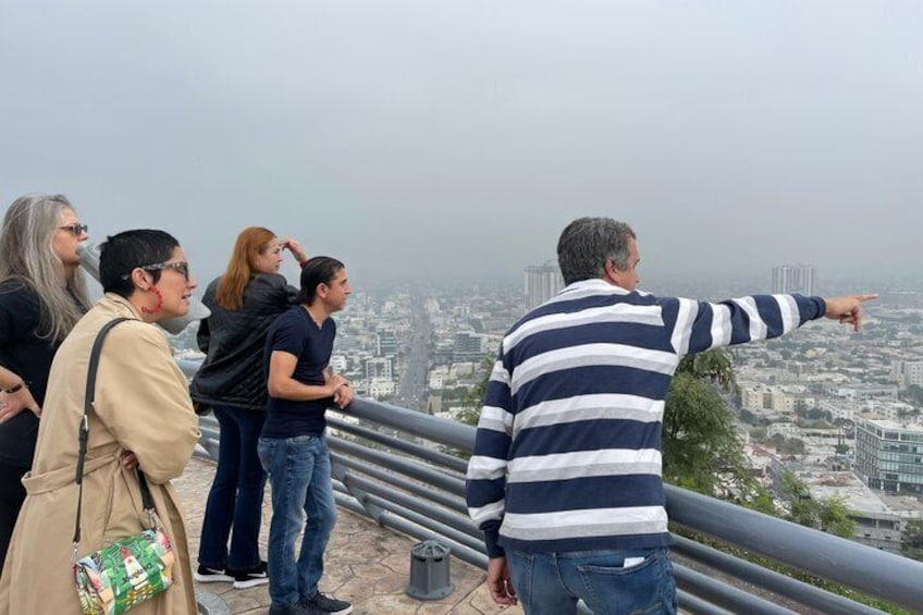 A group of people standing on a balcony overlooking a cityscape. 1