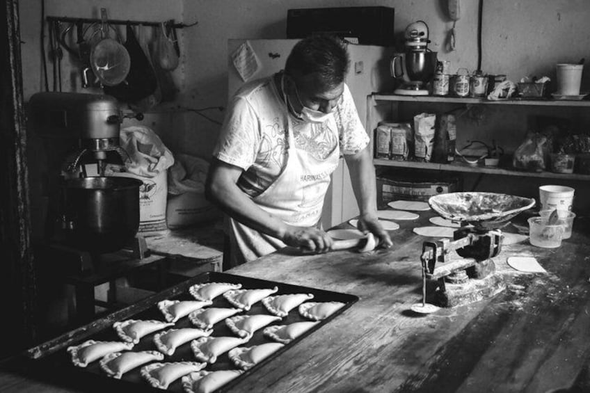 A person preparing food in a kitchen with a mixer, dough, and various kitchen utensils. 2