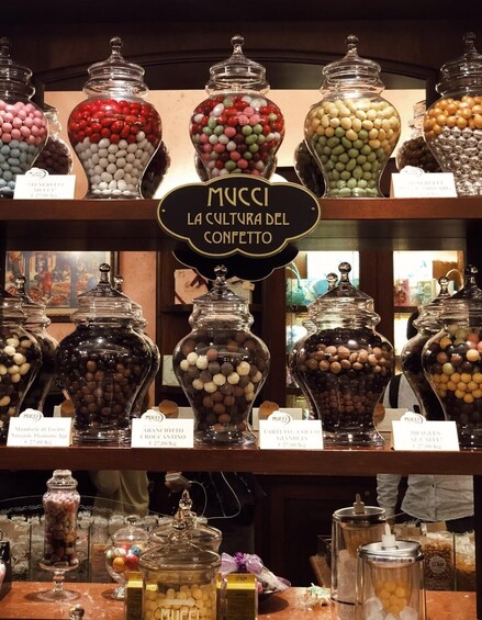 A variety of candy jars labeled with names and prices, indicating a confectionery store. 3