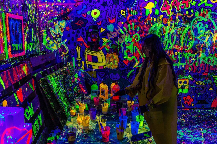 A person painting on a wall with vibrant graffiti and colorful paint splatters. 2