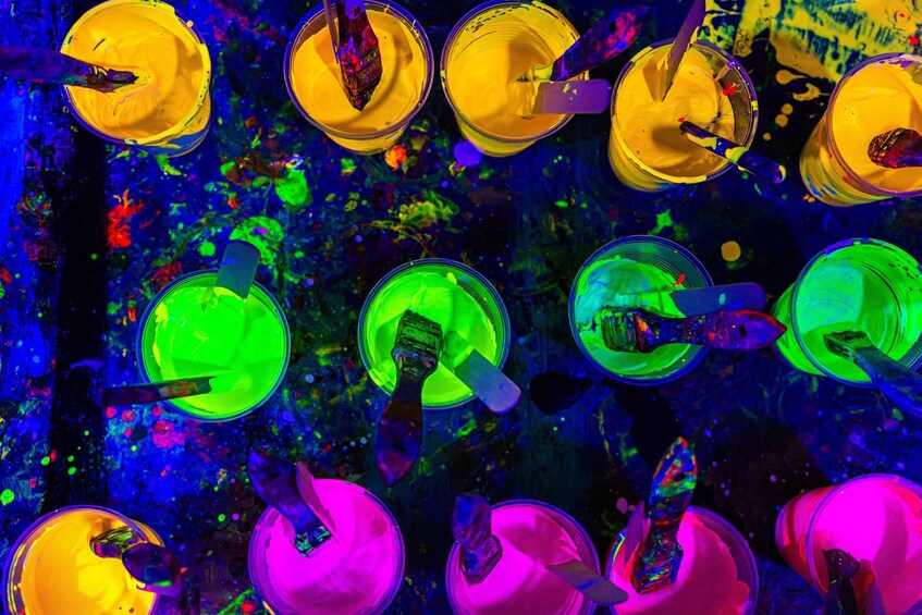 A collection of paint containers with brushes, set against a vibrant, abstract background. 4