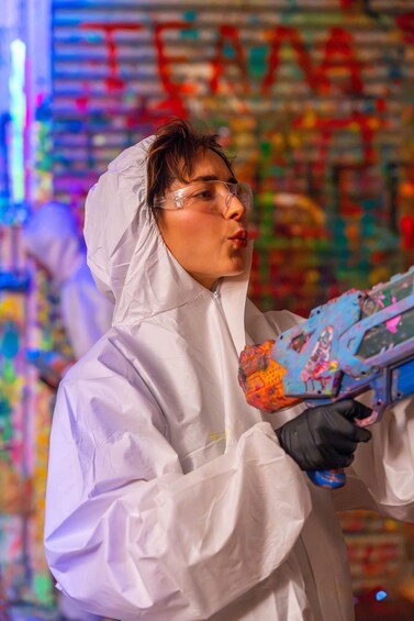 A person in a white protective suit holding a colorful spray paint can. 5