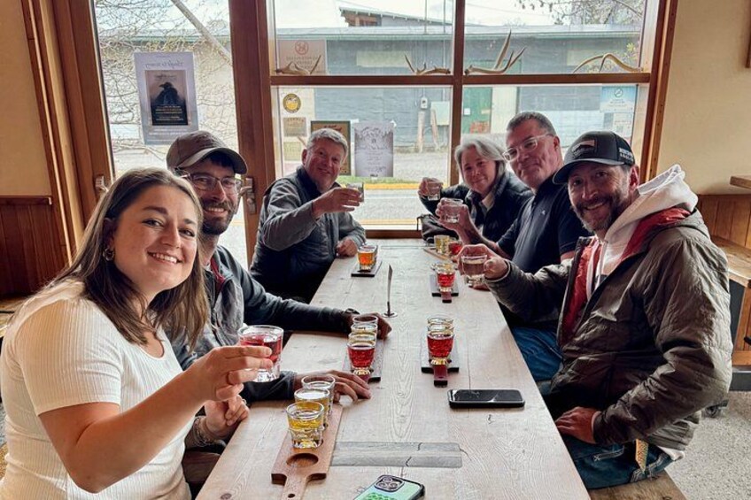 A group of people sitting at a wooden table in a restaurant, holding glasses of beer. 1