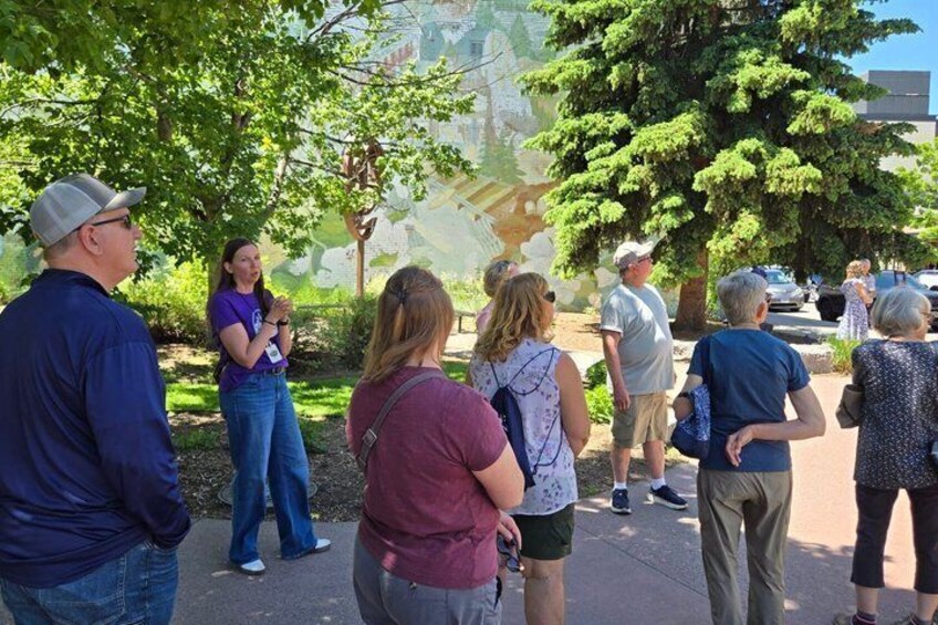 A group of people standing outdoors, possibly at a park or public space with trees and a clear sky. 4