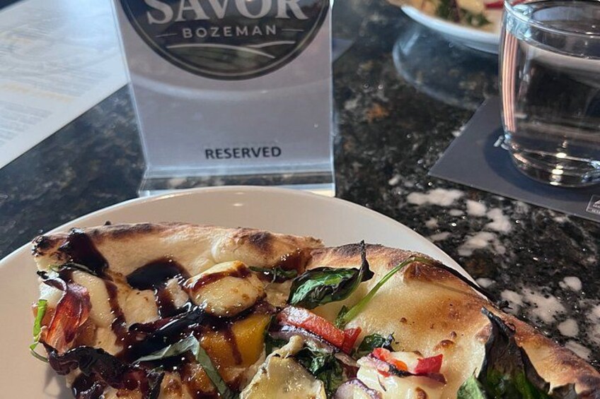 A pizza with toppings and a reserved sign in the background. 4
