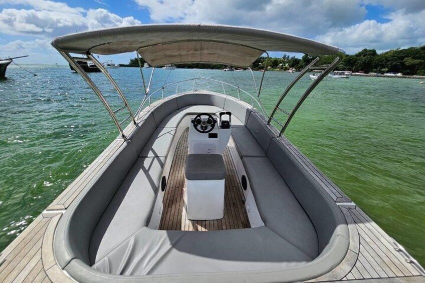 A boat's interior with a steering wheel, cushioned seating, and a wooden deck. 1