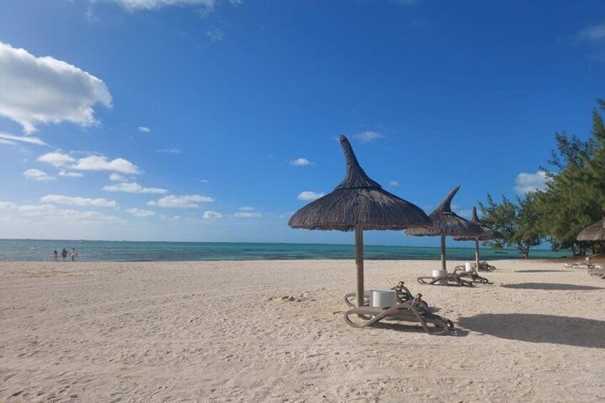 A beach with thatched umbrellas and lounge chairs. 4