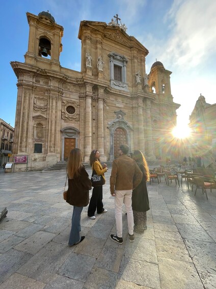 A historic church with a bell tower, a large arched doorway, and a statue on the facade. 2