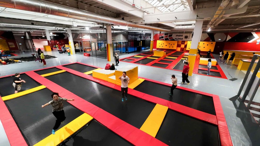 An indoor trampoline park with multiple trampolines and padded obstacles. 3