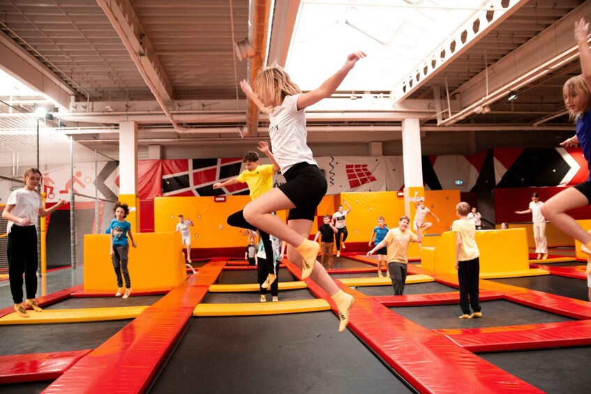 A trampoline park with multiple trampolines and people jumping. 1