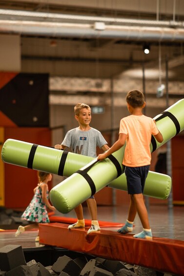 Children playing with large green foam rollers on a stage. 4