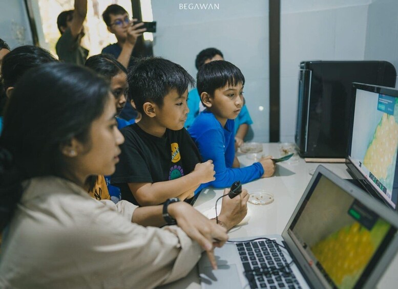 Children engaged in a computer-based activity, with a laptop and a tablet on the table. 5