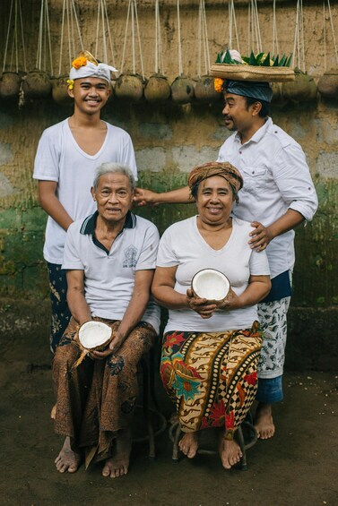 A group of people in traditional attire, with one individual holding a coconut. 3