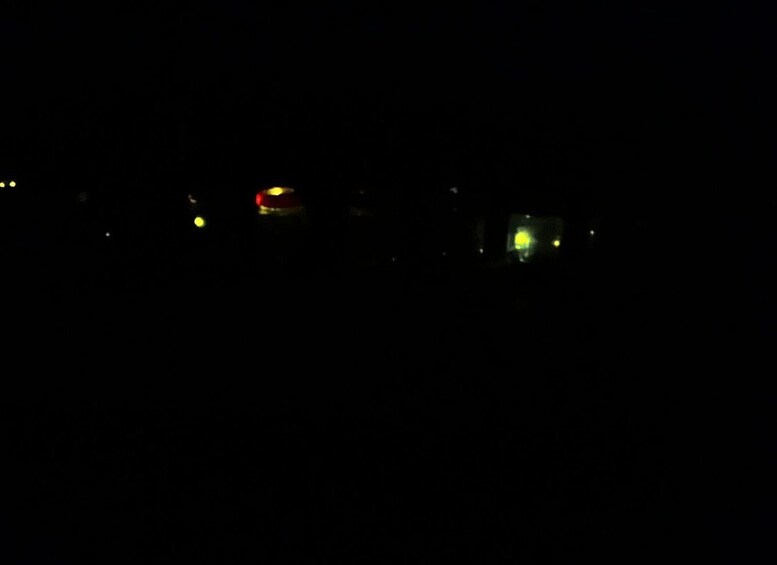 A dark night sky with a few distant lights, possibly buildings or streetlights. 4