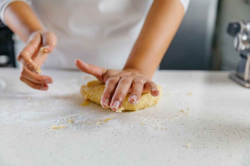 A person kneading dough on a kitchen counter. 2