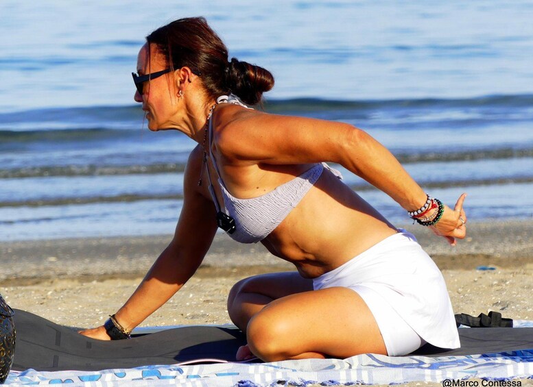 A person performing a yoga pose on a beach with the ocean in the background. 5