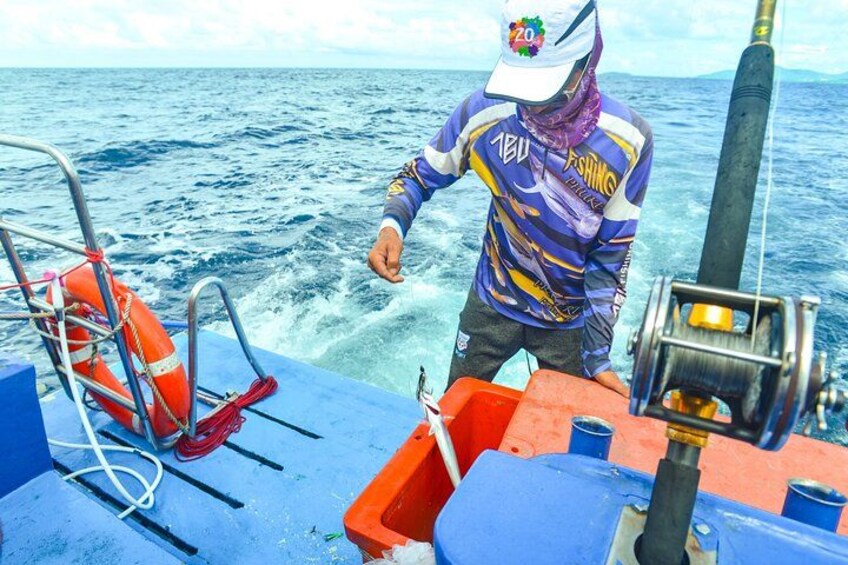 A person on a boat with a life preserver and a fishing rod. 4