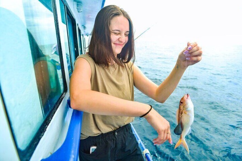 A person holding a fish on a boat. 1