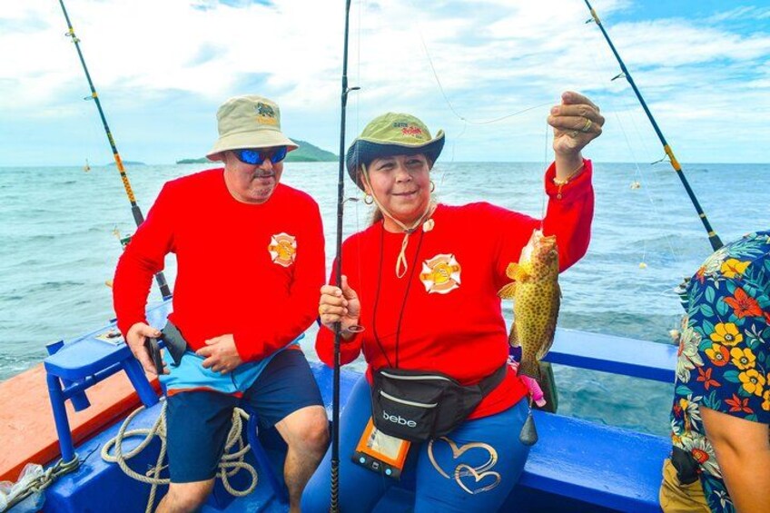 Two people on a boat holding a fish, with fishing rods and a blue boat. 5