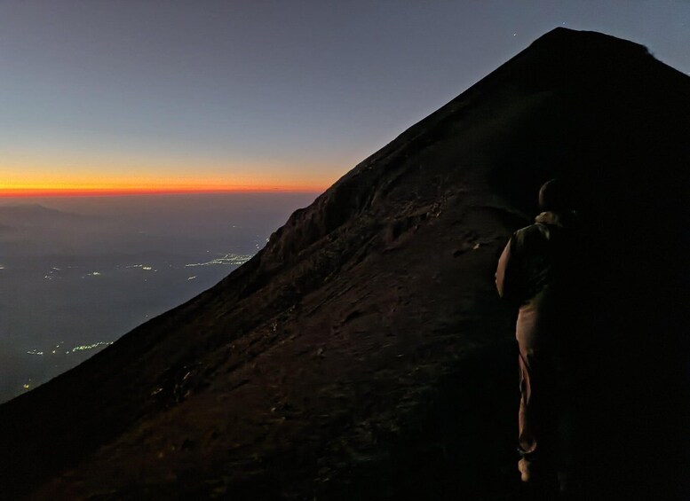 A mountain slope at sunset with a person climbing. 5