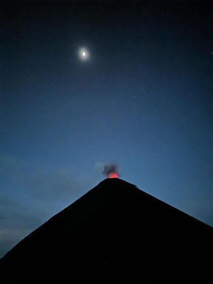 A night sky with a bright moon and a volcano emitting smoke. 3