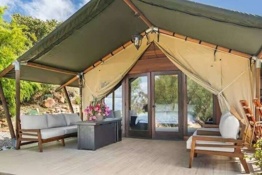 A tented outdoor area with a sofa, a coffee table, and a chair. 4