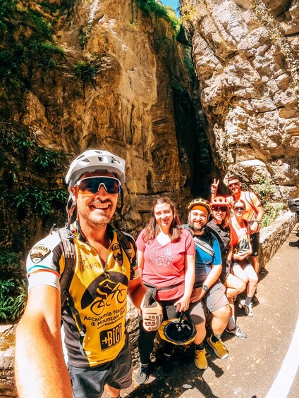 A group of cyclists on a mountain biking trail with rocky terrain and greenery. 4